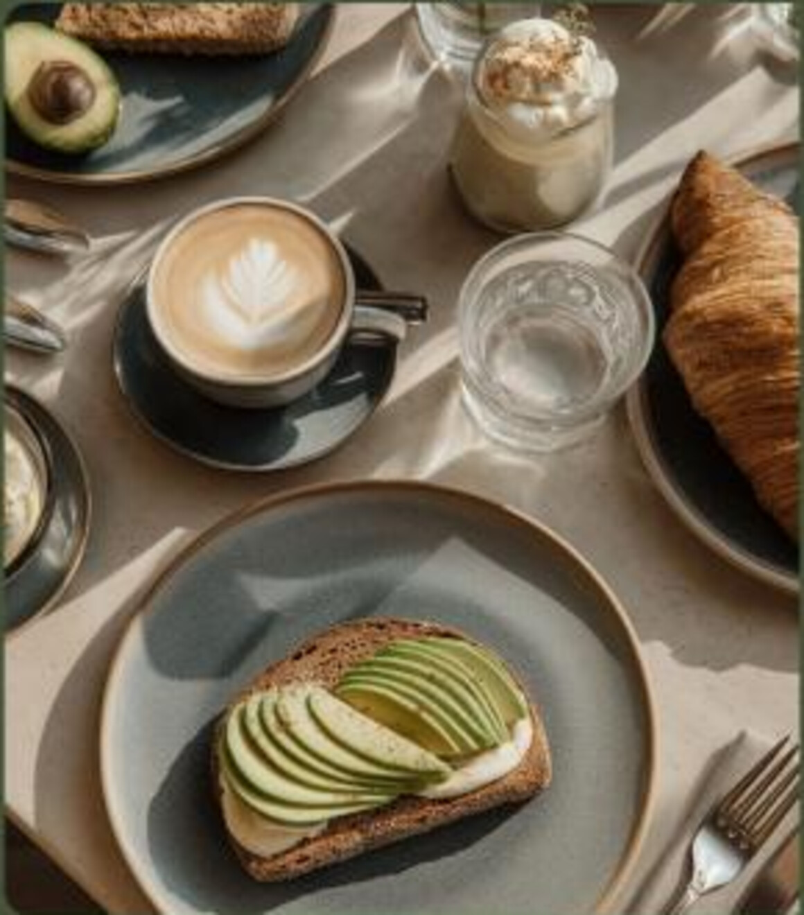 Coffee, pastry, and avocado toast arranged on a café table